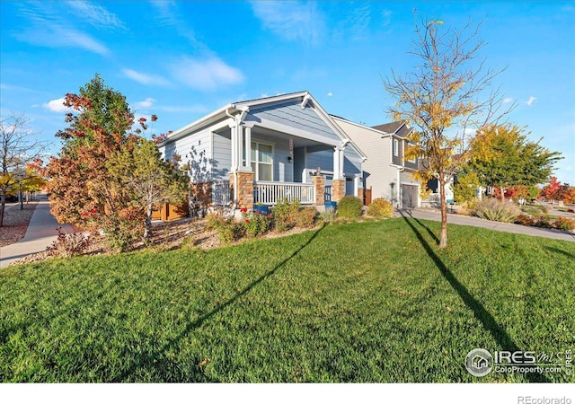 view of front of property featuring covered porch, a garage, and a front yard