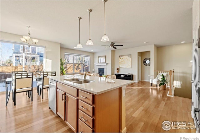 kitchen with dishwasher, sink, decorative light fixtures, a center island with sink, and ceiling fan with notable chandelier