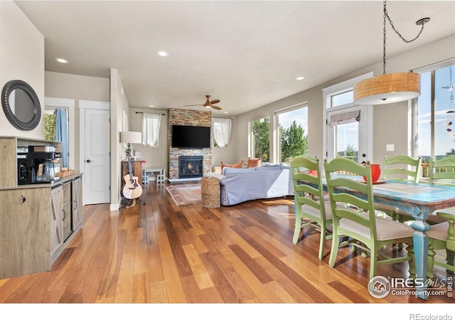 dining area with a fireplace, light hardwood / wood-style floors, and ceiling fan