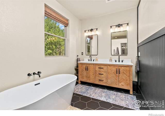 bathroom with tile patterned floors, a washtub, and vanity