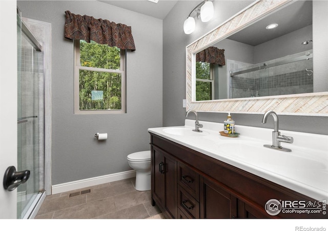 bathroom with tile patterned flooring, vanity, toilet, and a shower with shower door