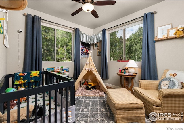 bedroom with ceiling fan and a crib