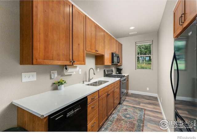 kitchen with black appliances, dark hardwood / wood-style floors, and sink