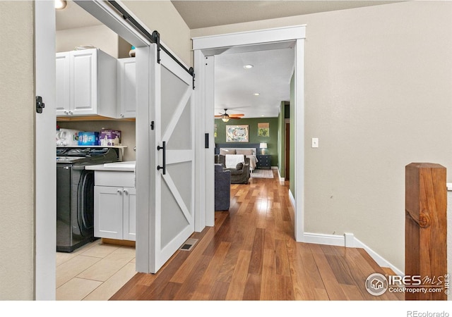 hallway featuring a barn door, washer / dryer, and light hardwood / wood-style floors