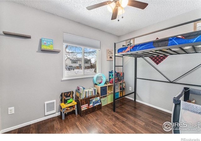 bedroom with ceiling fan, dark hardwood / wood-style floors, and a textured ceiling