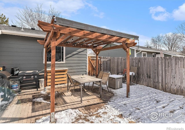 snow covered deck featuring a pergola, area for grilling, and a patio area