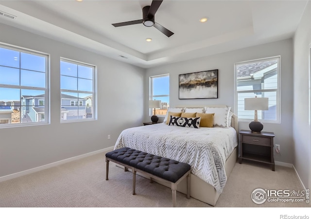 bedroom featuring a tray ceiling, multiple windows, and ceiling fan