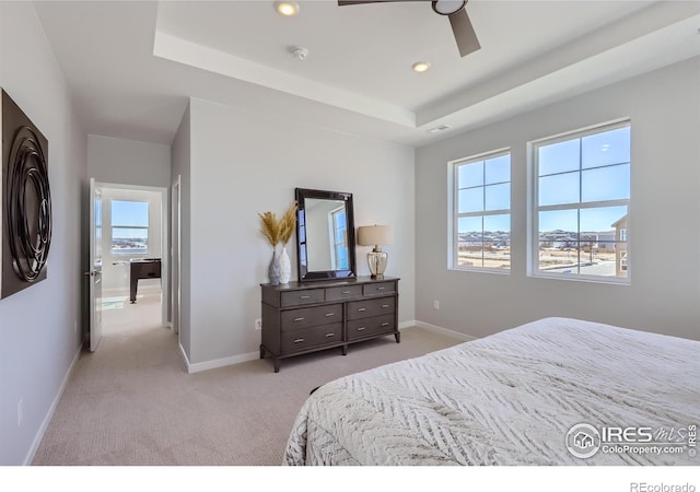 carpeted bedroom featuring a tray ceiling and ceiling fan