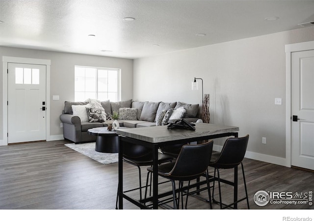 dining room with dark wood-type flooring and a textured ceiling