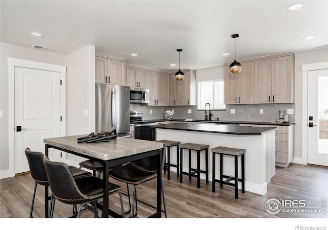 kitchen with pendant lighting, dark hardwood / wood-style flooring, stainless steel appliances, and a center island