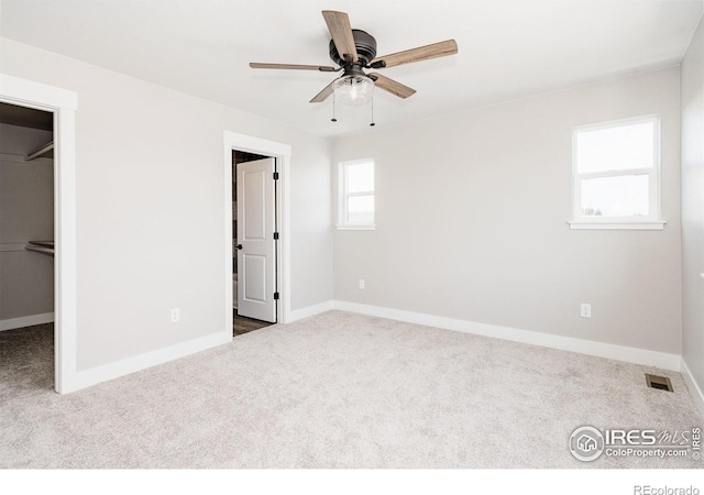 unfurnished bedroom with a spacious closet, a closet, ceiling fan, and carpet flooring