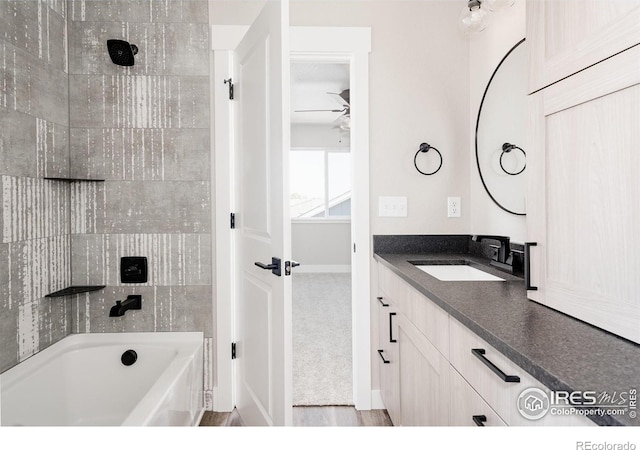 bathroom with tiled shower / bath combo, vanity, and ceiling fan