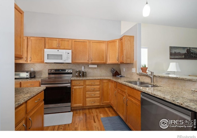 kitchen featuring backsplash, sink, light stone countertops, and stainless steel appliances