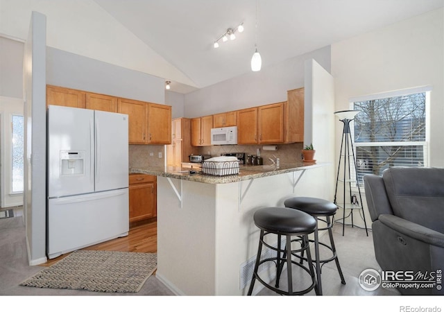 kitchen with kitchen peninsula, light stone countertops, backsplash, white appliances, and hanging light fixtures