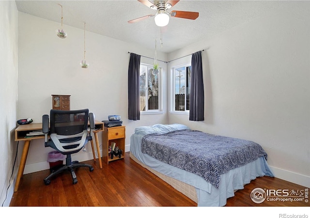 bedroom with ceiling fan, dark wood-type flooring, and a textured ceiling