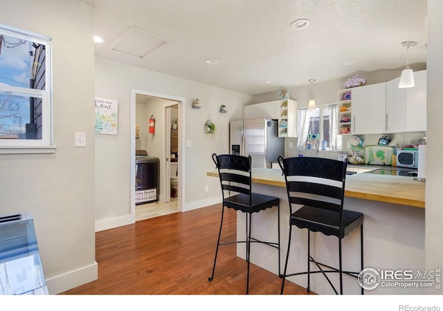 kitchen featuring a kitchen bar, stainless steel fridge with ice dispenser, butcher block countertops, and white cabinets