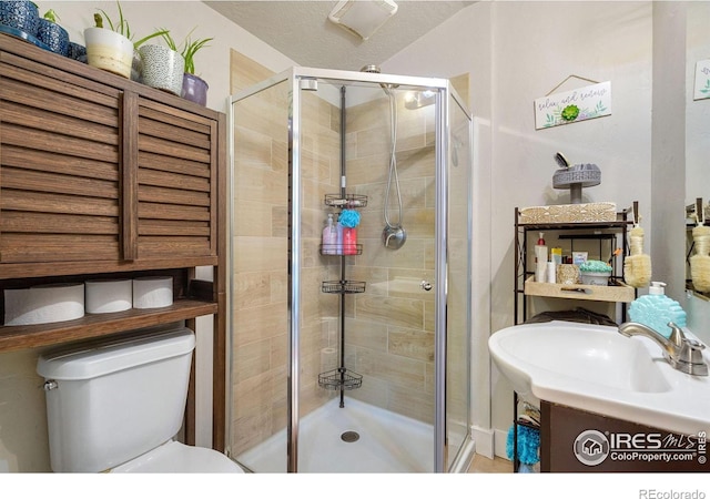 bathroom featuring toilet, vanity, a textured ceiling, and walk in shower