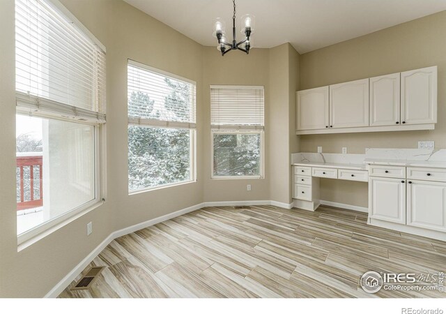 kitchen featuring white cabinetry, a notable chandelier, light hardwood / wood-style flooring, and pendant lighting