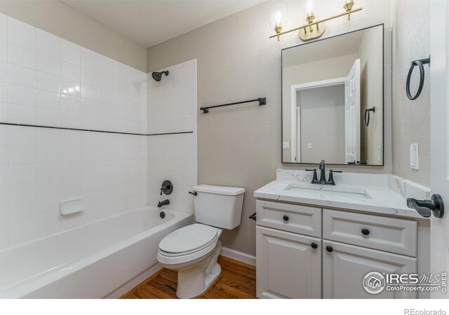 full bathroom featuring tiled shower / bath combo, wood-type flooring, vanity, and toilet