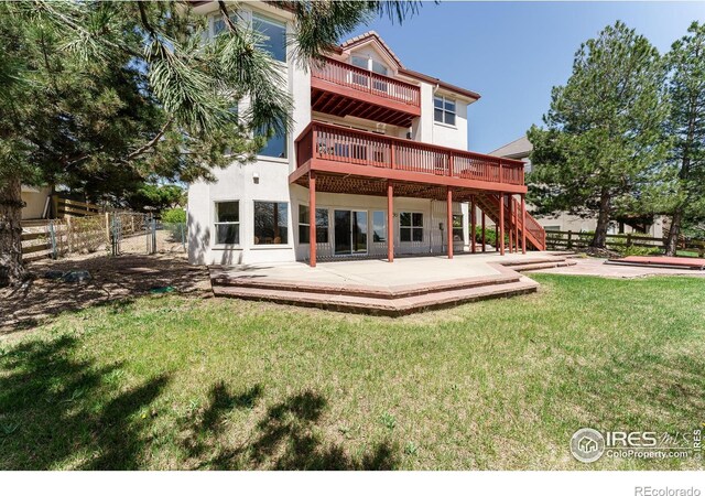 back of house with a wooden deck, a yard, and a patio area