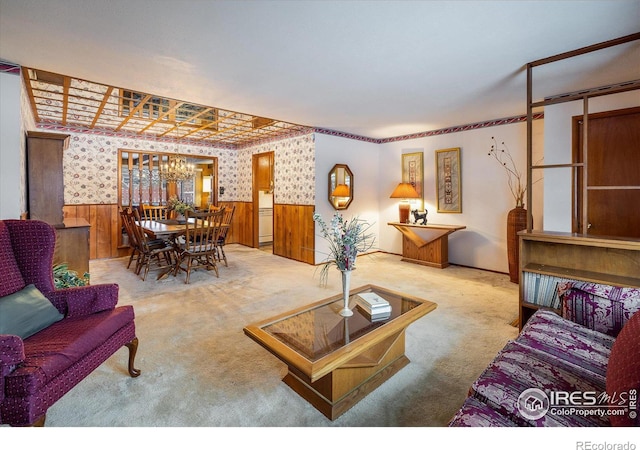 living room featuring wooden walls, light colored carpet, and a notable chandelier