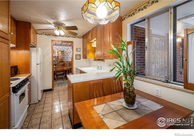 kitchen with ceiling fan, sink, kitchen peninsula, decorative light fixtures, and white appliances