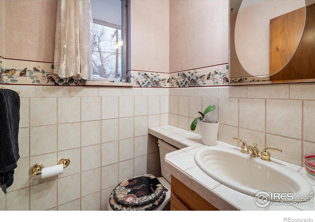 bathroom with vanity, toilet, and tile walls