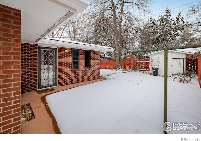 snowy yard with a storage unit