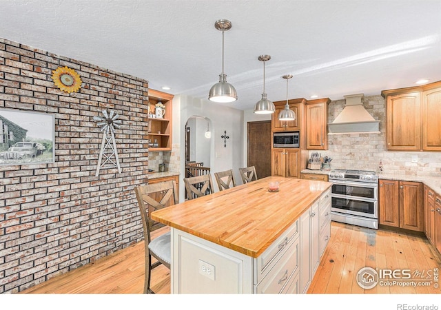 kitchen with a center island, butcher block countertops, decorative backsplash, appliances with stainless steel finishes, and custom exhaust hood