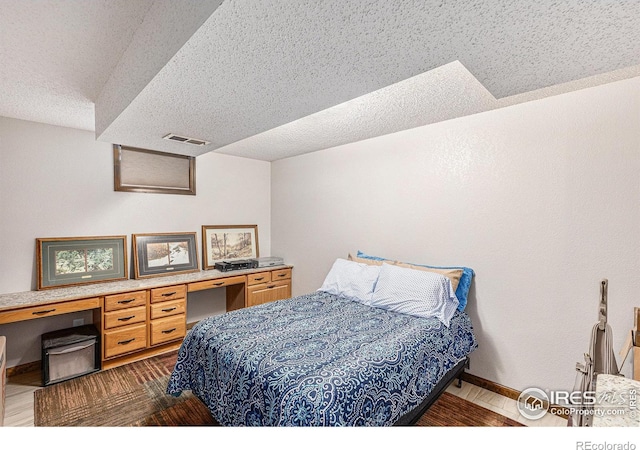 bedroom featuring built in desk and a textured ceiling