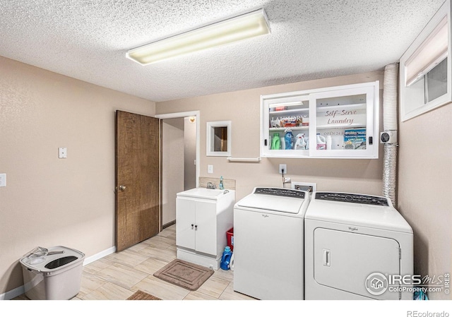 washroom with sink, cabinets, a textured ceiling, and independent washer and dryer