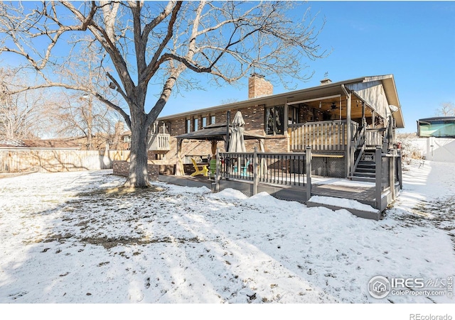 snow covered rear of property featuring a deck