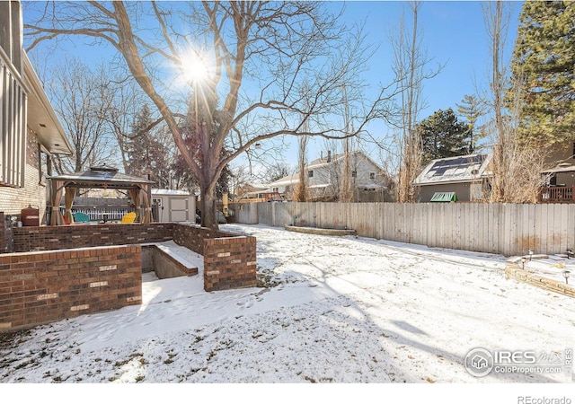 yard covered in snow with a gazebo and a shed