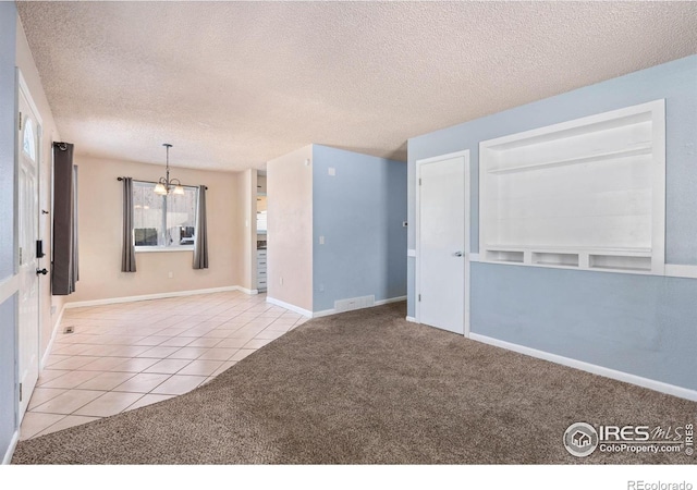 unfurnished room featuring a textured ceiling, an inviting chandelier, and light tile patterned flooring