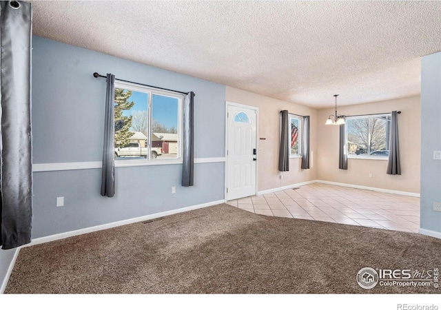 entryway featuring a wealth of natural light, light colored carpet, a textured ceiling, and an inviting chandelier