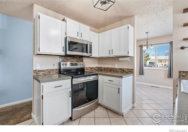 kitchen featuring pendant lighting, an inviting chandelier, light tile patterned flooring, white cabinetry, and stainless steel appliances