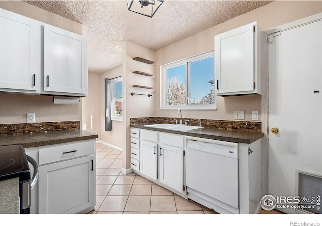 kitchen with dishwasher, sink, light tile patterned floors, a textured ceiling, and white cabinetry