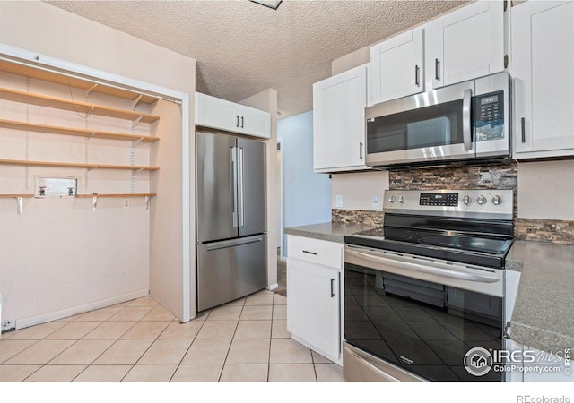 kitchen with decorative backsplash, appliances with stainless steel finishes, a textured ceiling, light tile patterned floors, and white cabinets