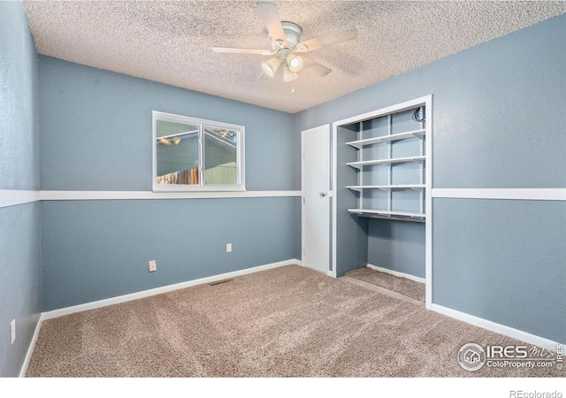 unfurnished bedroom featuring carpet, a textured ceiling, a closet, and ceiling fan