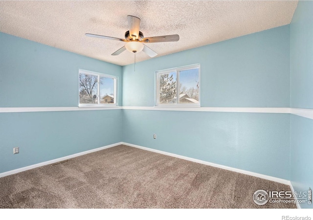 carpeted spare room featuring a textured ceiling, plenty of natural light, and ceiling fan