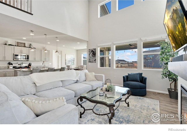 living room featuring a towering ceiling and light wood-type flooring