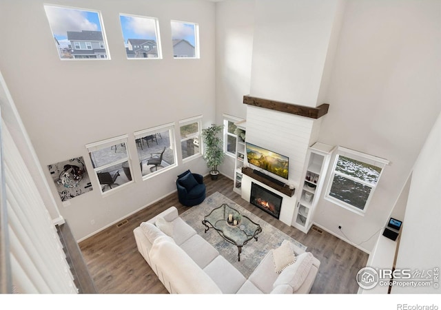 living room featuring hardwood / wood-style flooring, a fireplace, and a high ceiling