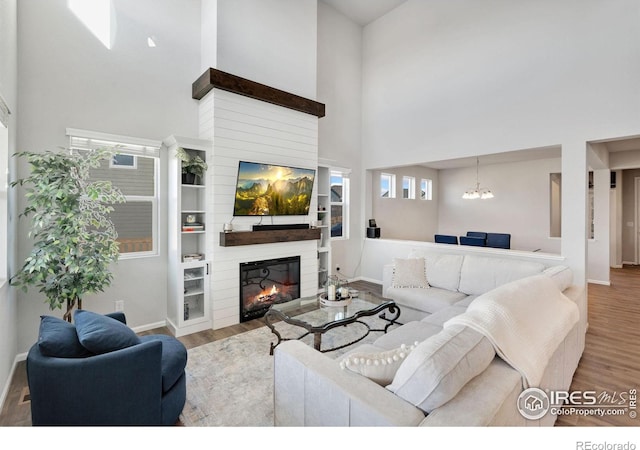 living room with hardwood / wood-style flooring, a notable chandelier, and a towering ceiling