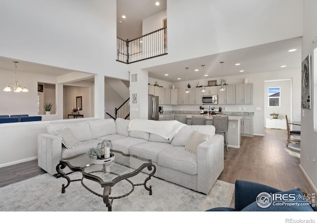 living room featuring a towering ceiling, light hardwood / wood-style floors, and a notable chandelier