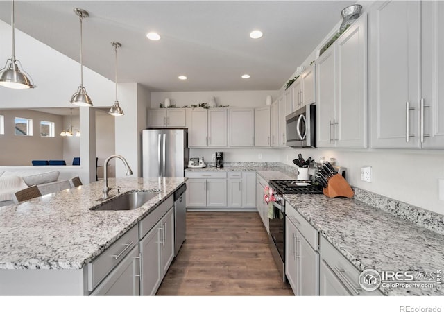 kitchen with appliances with stainless steel finishes, sink, decorative light fixtures, white cabinets, and an island with sink