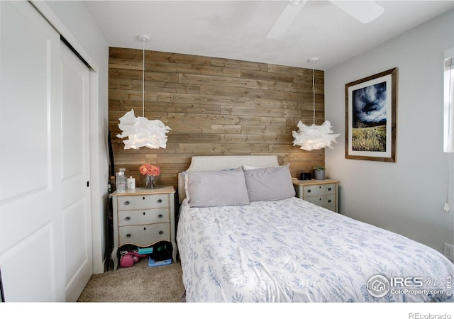 carpeted bedroom featuring a closet, ceiling fan, and wooden walls