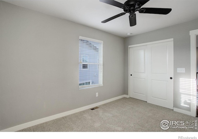 unfurnished bedroom featuring ceiling fan, light carpet, and a closet