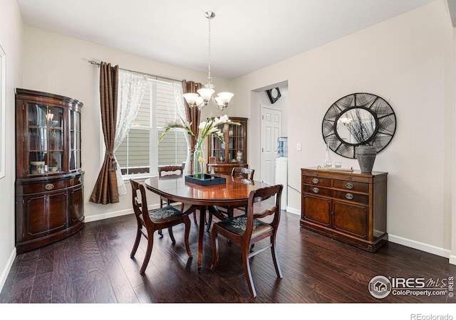 dining space with dark wood-style floors, baseboards, and a notable chandelier