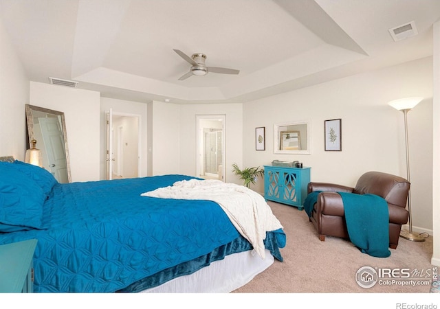 bedroom featuring light carpet, visible vents, a raised ceiling, and a ceiling fan