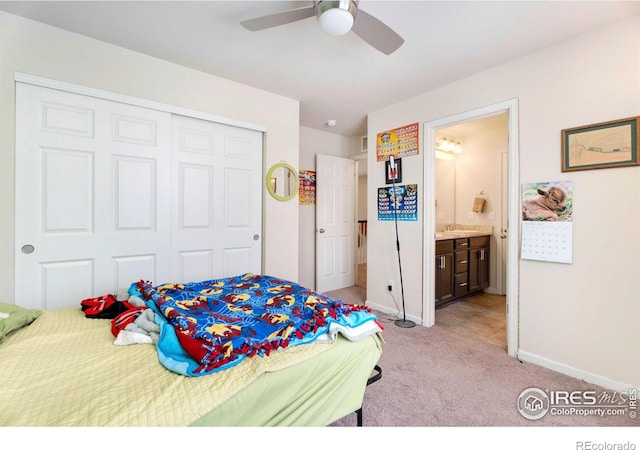 bedroom with light carpet, a closet, baseboards, ensuite bath, and a sink